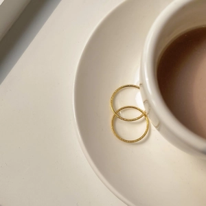 Minimalist matte gold titanium rings on a white ceramic saucer in elegant soft lighting