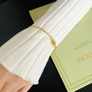 Close-up of a minimalist gold bracelet with a lock pendant on a woman's wrist