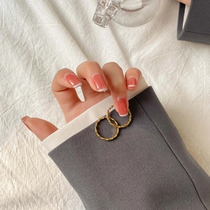 Ensemble de bagues dorées élégantes avec perles porté par femme en blazer gris