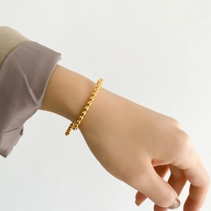 Detailed view of a minimalist rose gold bead bracelet on a wrist with white background