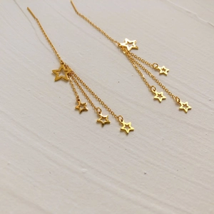 Close-up of gold star tassel earrings with long chain fringe for a minimalist look