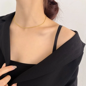 Dettaglio di una collana minimalista a sfere placcata oro 18K sul collo di una modella