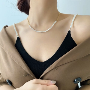 Detailed view of artificial pearl and golden metal chain necklace on model neck