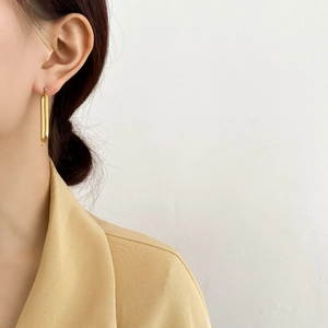 Primo piano di orecchini a torsione a forma di U dorati indossati da una modella elegante