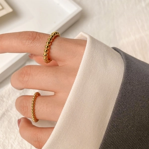 Polished gold beaded titanium steel rings in two sizes for minimalist layering on a tray