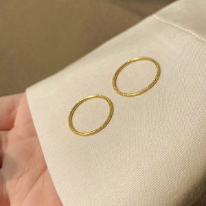 Macro shot of two slim gold frosted rings with sandblast finish on silk cushion