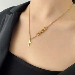 Gros plan d'un collier croix doré avec des détails de maillons de chaîne épais