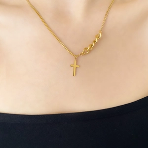 Détail du collier à chaîne asymétrique dorée avec pendentif croix sur modèle