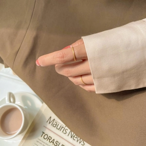 Detailed view of two minimalist frosted gold rings with textured finish on fingers