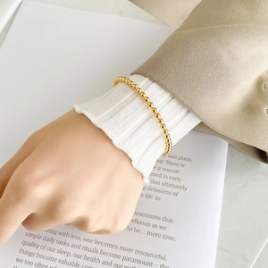 Close-up of minimalist gold beaded bangle on wrist against elegant lifestyle backdrop