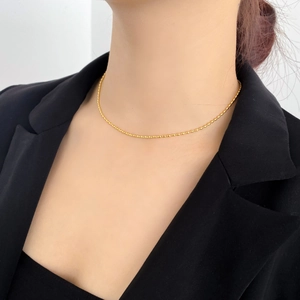 Primo piano di una collana girocollo a grani dorati indossata con un blazer scuro