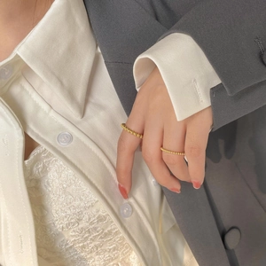 Detail of minimalist gold-plated beaded stacking rings worn with casual attire