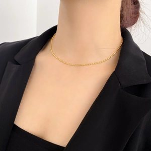 Dettaglio di una collana girocollo a sfere placcata in oro indossata su un blazer