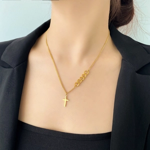 Collier croix doré chic avec chaîne asymétrique porté par un mannequin de mode