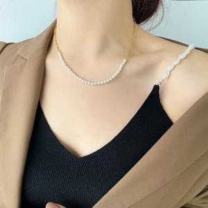 Close-up of pearl and gold chain link necklace worn with a brown blazer suit