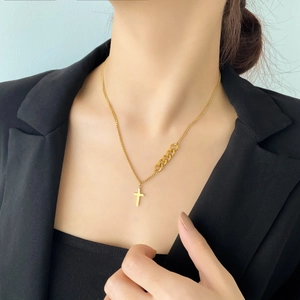 Collier croix doré asymétrique avec chaîne à maillons gourmette sur un mannequin en costume