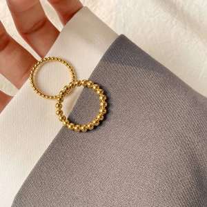 Detail of minimalist beaded gold plated titanium steel rings stacked on hand