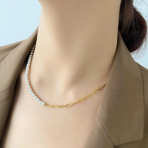 Detail of half pearl half gold chain necklace on a model wearing a brown blazer