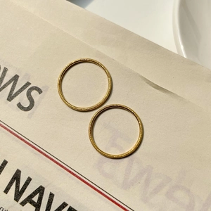 Close-up of minimalist gold-toned matte rings on a vintage paper background