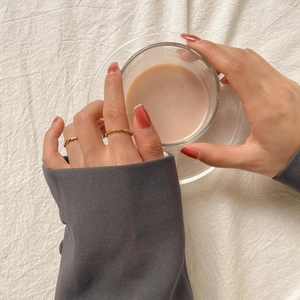 Détail de bagues élégantes dorées minimalistes à perles et torsadées sur un doigt