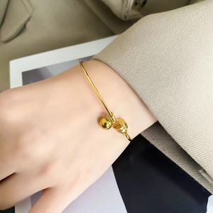 Detailed view of a gold minimalist cuff bracelet with geometric sphere and cylinder charms
