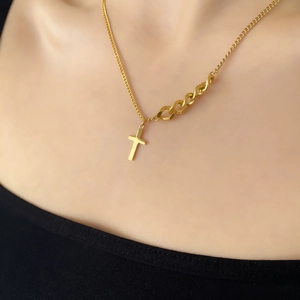 Détail du pendentif croix dorée avec chaîne asymétrique et maillons cubains sur modèle