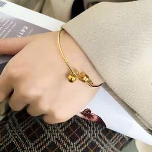 Detailed view of a minimalist gold bangle with round bead charms worn on wrist