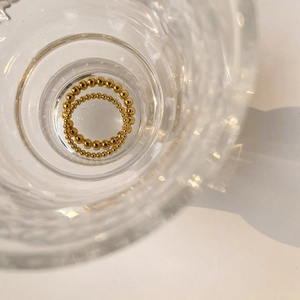 Macro detail of gold beaded stackable rings set inside an elegant carved glass