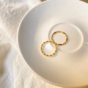 Gros plan d'un ensemble de bagues dorées à perles et carrées sur un plateau chic