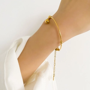 Detailed view of a gold minimalist pearl bracelet with an adjustable chain on a wrist