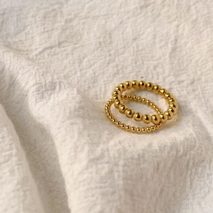 Detail of two minimalist gold plated bead rings on a textured cream linen background