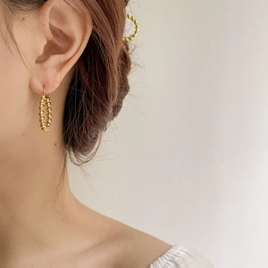 Close-up of golden beaded hoop earring worn by a model in a minimalist luxury setting