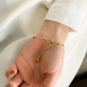 Close-up of minimalist gold pearl bangle bracelet worn on wrist with white shirt