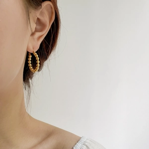 Detailed view of bohemian gold beaded hoop earrings worn on a female model