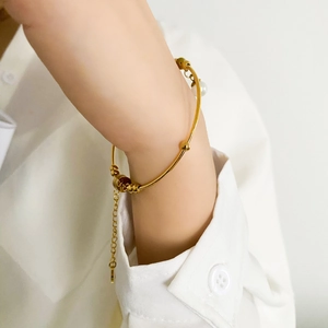 Detailed shot of a gold minimalist bracelet with a pearl charm on a model's wrist