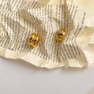 Boucles d'oreilles géométriques dorées à double couche sur des pages de livre vintage