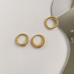 Détail de trois bagues torsadées dorées style croissant sur une surface de miroir design