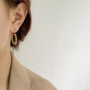 Close-up of elegant gold beaded hoop earrings worn with professional business attire