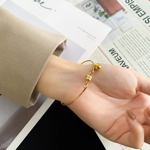 Detail of minimalist gold pearl bangle with magnetic clasp on beige blazer background