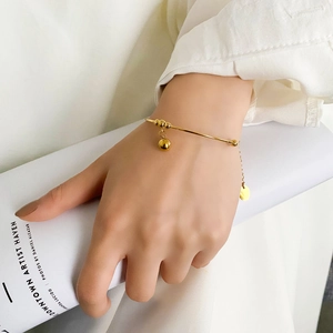 Detail of a gold minimalist pearl bracelet with spherical charms worn on a wrist