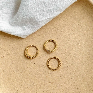 Trois bagues torsadées dorées avec un anneau croissant sur une surface texturée naturelle
