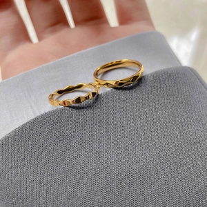 Makro-Detail des facettierten Gold-Titanstahl-Rings im französischen Design auf Stoff