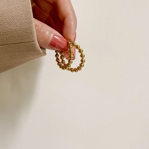 Minimalist gold beaded hoop earrings shown in hand for actual size and texture