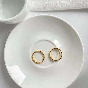 Minimalistische goldene geometrische Ringe auf einer weißen Keramik-Schmuckschale