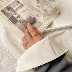 Minimalist 18K gold plated titanium rings shown on model with one classic band and one stone