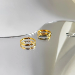 Makroaufnahme von zwei facettierten goldenen Titanringen mit modernen Wellenmustern
