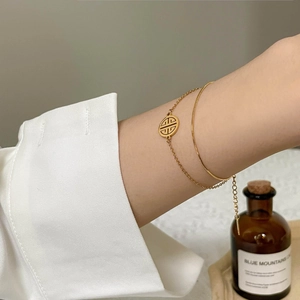Close-up of a double-layered gold-plated snake chain bracelet with hollow round charm