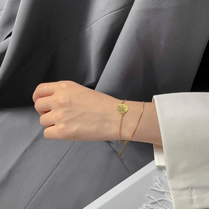 Detail of double-layer gold plated bracelet with snake chain and lucky pendant