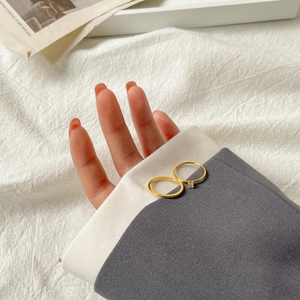 Detail of two minimalist 18K gold plated titanium rings shown on hand with elegant clothing