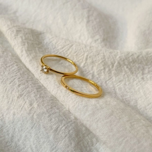 Close-up of 18K gold plated titanium ring set with round cut cubic zirconia on fabric